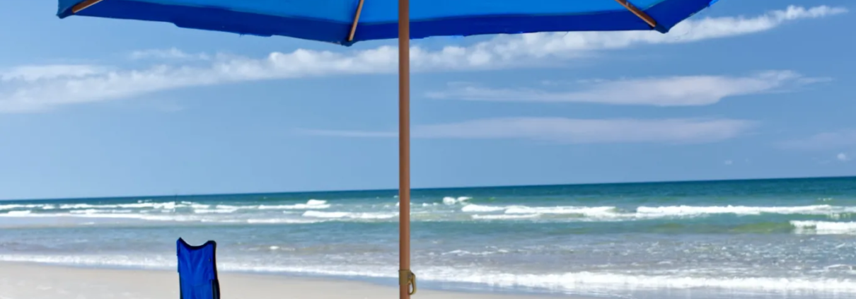 Blue beach umbrella with blue chair on beach with ocean waves