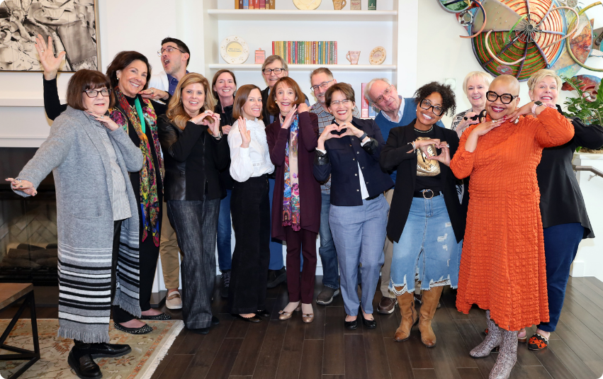 Color photograph of Gilda's Club Kentuckiana's board of directors in fun poses standing in the lobby of Gilda's Grinstead location.