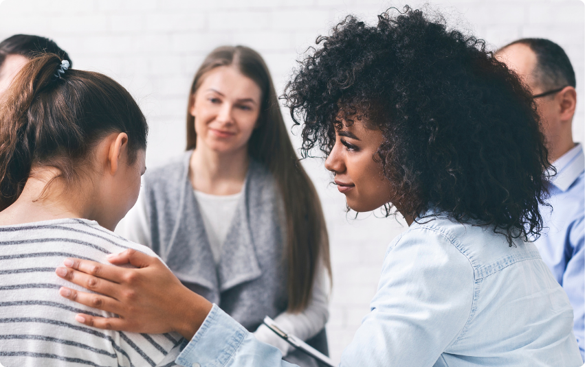 Color photo of woman in group comforting another woman with her hand on the other's shoulder